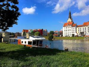 a boat on a river in front of a building at HOUSEBOAT Mazury Frajda in Giżycko