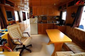 a kitchen with a table and a chair in a trailer at HOUSEBOAT Mazury Frajda in Giżycko