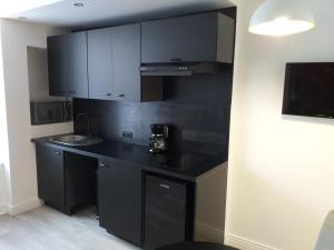 a kitchen with a black counter and a sink at Les Volets Bleus - Au Calme avec petit Jardin et Patio - 3 appartements in Bourges +22 photos
