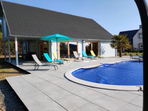 une piscine avec des chaises et un parasol dans l'établissement Gîte Ker Koad, à Pluduno