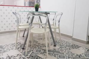 una mesa de cristal y 4 sillas blancas en la cocina en Nube Imperial, en Salamanca