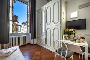 Zimmer mit einem Schreibtisch, einem TV und einem Fenster in der Unterkunft Duomo Palace in Florenz