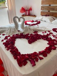 two swans are forming a heart on a bed with roses at Pousada Dolce Vita in Itanhaém