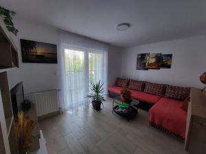a living room with a red couch and a window at Apartman Šarm Srebrno jezero in Veliko Gradište