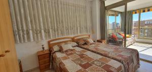 a bedroom with two beds and a large window at ADELFAS - Fincas Arena in Benidorm +21 photos