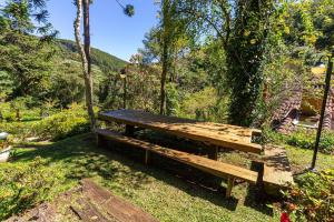 un banco de madera sentado en el césped en un parque en Vale do Lajeado - Mountain chalets, en Campos do Jordão