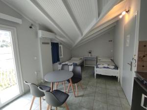 a room with two beds and a table and chairs at Venus Rooms in Katelios