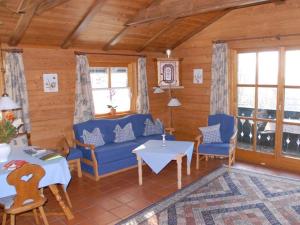 a living room with a blue couch and tables and windows at Waldhofalm Angerer in Berchtesgaden