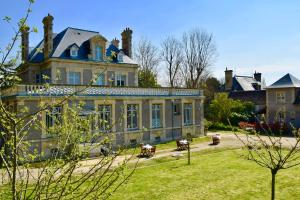 a large house with a blue roof and a yard at Chambres d'Hôtes Le Clos des Marronniers in Douvres-la-Délivrande