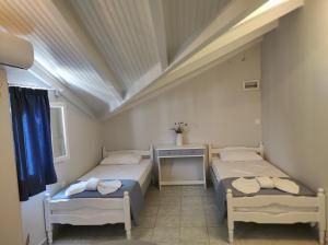 a room with two beds and a table in it at Venus Rooms in Katelios