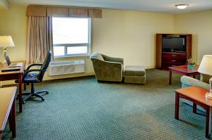 um quarto de hotel com uma secretária e cadeiras e uma televisão em Nova Inn Acheson em Spruce Grove
