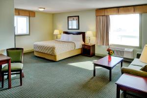 um quarto de hotel com uma cama e uma cadeira em Nova Inn Acheson em Spruce Grove