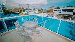 um pátio com uma mesa e cadeiras ao lado de uma piscina em Hotel Palma Linda em Coveñas