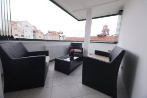 einen Balkon mit Stühlen, einem Tisch und einem Fenster in der Unterkunft Harmony Apartmani Arandjelovac in Aranđelovac