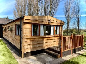 a wooden cabin with a porch and a window at Poplar Lodge Log Caravan in Kirkby on Bain