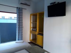 Cette chambre comprend un lit, une télévision et une fenêtre. dans l'établissement Pousada Bela Paraty, à Parati