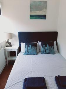 a bed with blue and white sheets and a night stand at Cosy 1 Bedroom Apartment in the Heart of Llandudno in Llandudno