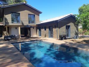 uma piscina em frente a uma casa em Agréable Villa Domaine du Golf Piscine CHAUFFEE em Biscarrosse