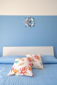 a bed with two pillows and a clock on it at VICOLO A MARE in Siracusa