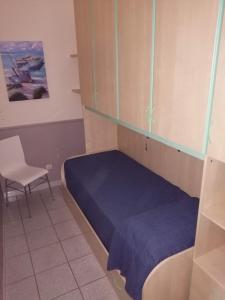 una piccola camera con letto blu e sedia di La Terrazza Zen a Catania