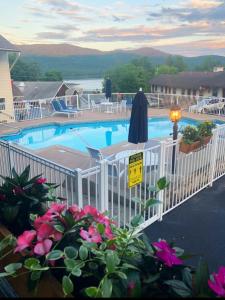 a swimming pool with a white fence and pink flowers at Nordick's Inn in Lake George