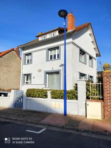 a white house with a blue pole on a street at Appart Le Crotoy Bécassine 50mètres Plage,centre. in Le Crotoy