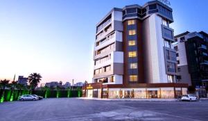 a large building with cars parked in a parking lot at MAJURA HOTEL BUSINESS in Karşıyaka