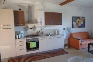una cucina con piano cottura e un divano in camera di Piscina e vistalago CroceMenaggio CIR 013145-00318 a Menaggio Altre 12 foto