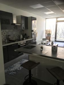 a kitchen with a counter and two stools in it at L’appartement charmant in Dole