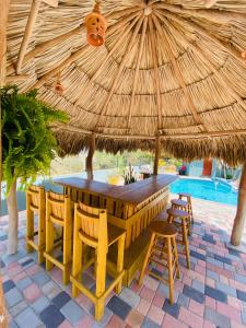 een houten tafel en stoelen onder een rieten paraplu bij La Felicidad Aruba in Oranjestad