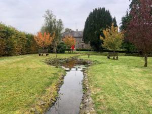 a park with two benches and a stream in the grass at Lacken Millhouse and Gardens in Cavan