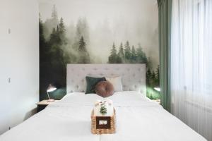 a bedroom with a large white bed with a forest wallpaper at Penzion Dubina in Litoměřice