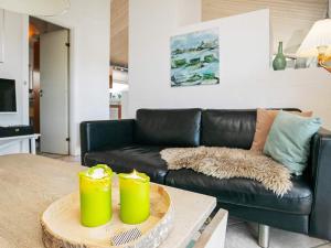 ein Wohnzimmer mit einem schwarzen Sofa und einem Tisch in der Unterkunft Three-Bedroom Holiday home in Pandrup 8 in Blokhus
