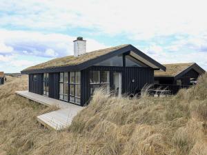 a black house on a hill in a field at Three-Bedroom Holiday home in Pandrup 8 in Blokhus
