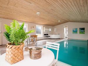 ein Haus mit einem Pool und einem Tisch mit einer Pflanze in der Unterkunft Three-Bedroom Holiday home in Pandrup 8 in Blokhus