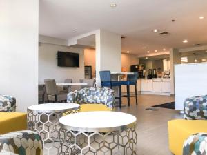 Microtel Inn & Suites by Wyndham Eagan/St Paul في ايجان: غرفة انتظار مع طاولات وكراسي ومطبخ