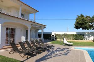 eine Gruppe von Stühlen auf einer Terrasse neben einem Pool in der Unterkunft Casa Alves - Villa with private heated swimming pool in Olhos de Água