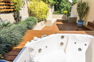 a white bath tub sitting on a deck with plants at Casas com jacuzzi e churrasqueira a 500 metros da Praia do Perequê na Ilhabela in Ilhabela