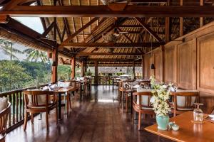 a restaurant with wooden floors and tables and chairs at Amandari in Ubud
