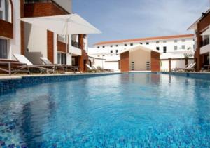 una gran piscina con sillas y sombrilla en Apartamento Deluxe para Parejas en Punta Cana, en Punta Cana