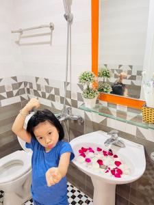 a little girl standing in front of a bathroom sink at Thanh Trung Hotel in Cat Ba