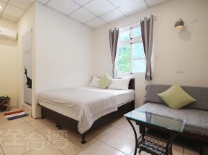綠島鄉的住宿－上園民宿，一间卧室配有一张床、一张沙发和一个窗口