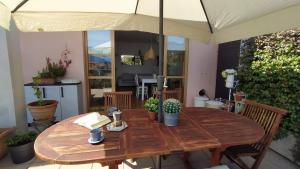 a wooden table with an umbrella on a patio at Appartamento La terrazza di Dora in Menaggio