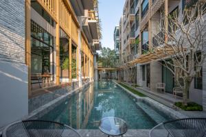 a swimming pool between two buildings with tables and chairs at SHAN Villas Sukhumvit ฌานวิลล่า สุขุมวิท in Bangkok