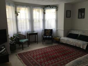 ein Wohnzimmer mit einem Sofa, Stühlen und Fenstern in der Unterkunft Garden flat 1 in Llandudno
