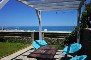 a picnic table and two chairs with a view of the ocean at Amazing beach house in Chorefto