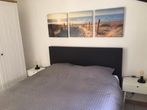 a bedroom with a bed with four paintings on the wall at Strandjutter huisje 8 in Middelkerke