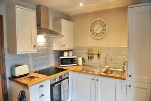 a kitchen with white cabinets and a clock on the wall at Beach View in Benllech