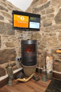 a fireplace with a tv on a stone wall at Beach View in Benllech