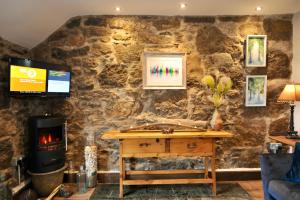 a living room with a stone wall with a wood stove at Beach View in Benllech